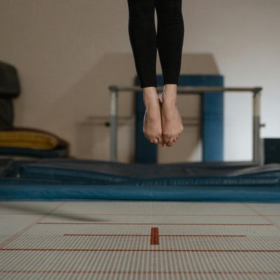 Person joyfully jumping in the air against a bright background.
